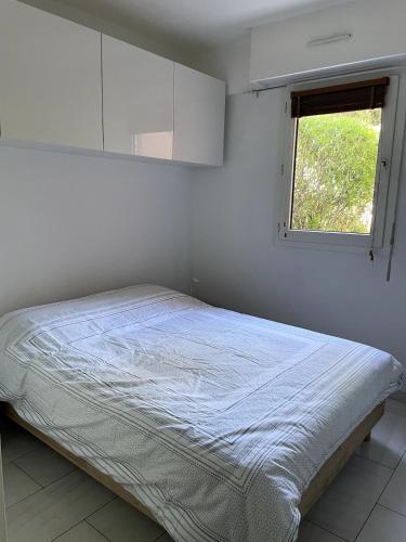 un lit dans une chambre blanche avec une fenêtre dans l'établissement appartement cosy avec piscine, à Saint-Raphaël