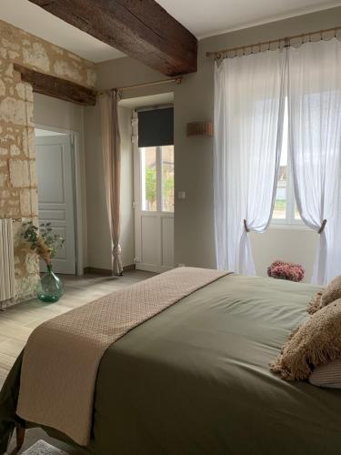 a bedroom with a large bed and two windows at La Gouronerie in Parçay-sur-Vienne