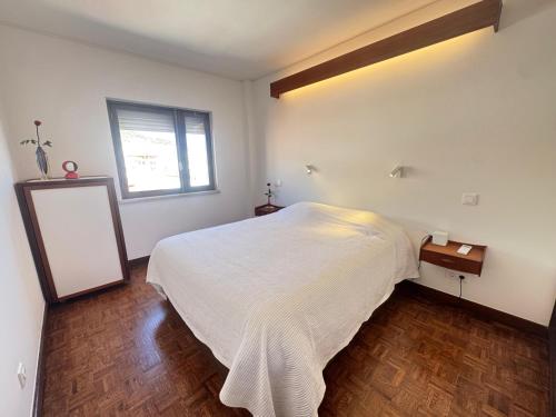 a bedroom with a white bed and a window at Sesimbra Universal in Sesimbra