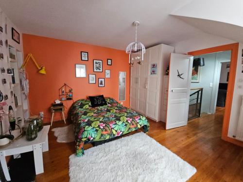 - une chambre avec un lit et un mur orange dans l'établissement Chambre familiale chez l'habitant, au Mans