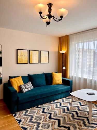 a living room with a blue couch and a table at SUNSET Apartment Near Sea - Family Friendly space with Bath and Good Coffee in Ventspils