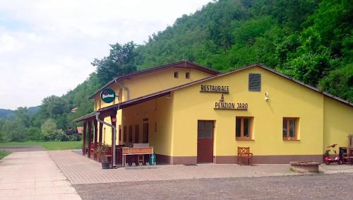 a yellow building in front of a mountain at Penzion a Restaurant Jaro in Hostěradice
