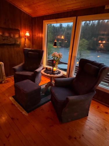 a living room with two chairs and a table and windows at Lakeside cabin in Snofugl