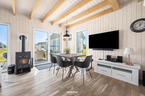 une salle à manger avec une table, une télévision et une cheminée dans l'établissement Ferienhaus Meerweh Olpenitz, à Olpenitz