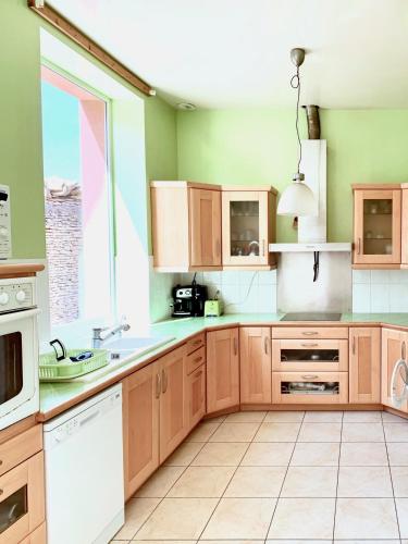 une cuisine avec des placards en bois et une grande fenêtre dans l'établissement Spacious & bright property on D-Day Beaches, à Ver-sur-Mer