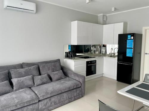 ein Wohnzimmer mit Sofa und eine Küche in der Unterkunft Apartament Aqua Mazury z jacuzzi in Lyck