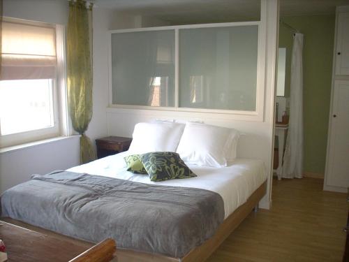una camera da letto con un grande letto con cuscini bianchi di B&B Pottebreker a Vlamertinge