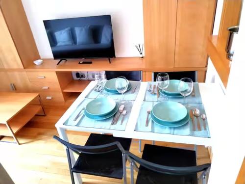 a table with plates and glasses and a television at Areropuerto Wanda en Plenilunio 3 3 B in Madrid
