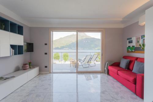 a living room with a red couch and a balcony at Misultin House & Swimming pool, Luxury in Lake Como by Rent All Como in Pianello Del Lario