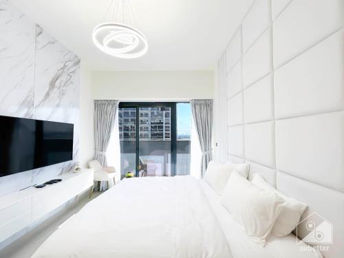 a white bedroom with a large bed and a tv at Luxury Living in Azizi Riviera l Cozy Balcony in Dubai