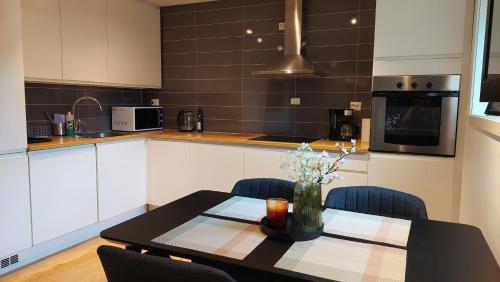 une cuisine avec une table avec un vase de fleurs dessus dans l'établissement BRUNØST APARTMENT modern apartment close to city center with free parking, à Tromsø
