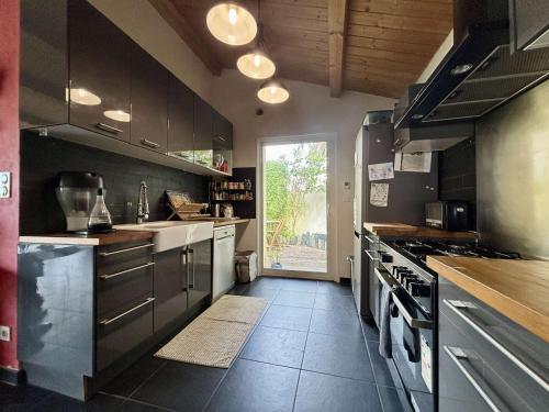 une grande cuisine avec des armoires noires et une fenêtre dans l'établissement Maison 4 pièces avec parking et terrasse à Saint Georges d'Oléron - FR-1-246A-355, à Saint-Georges-dʼOléron