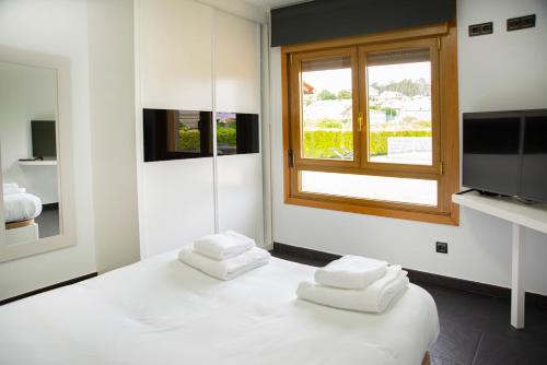Una habitación blanca con una cama con toallas. en Welcome Villa O Sidrón, 