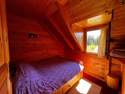 a bedroom in a log cabin with a purple bed at Guest House Milena in Žabljak