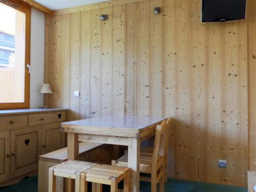 - une table et des chaises dans une chambre dotée de murs en bois dans l'établissement Charmant studio lumineux avec balcon sud, skis aux pieds, proche commerces, pour 4 personnes - FR-1-182-11, à Méribel