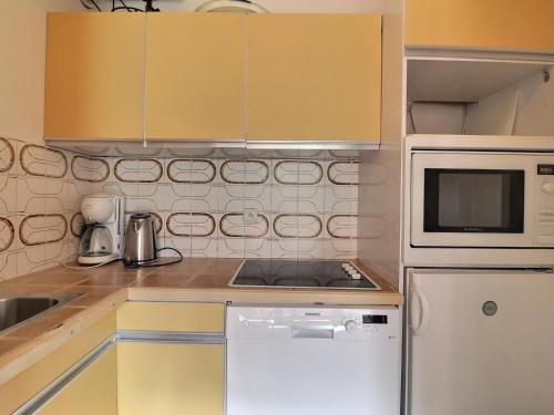 une cuisine avec des armoires jaunes et un four micro-ondes blanc dans l'établissement Appartement ensoleillé avec TV, proche pistes et commerces, Résidence Plein Soleil, Les Allues - FR-1-182-18, à Méribel
