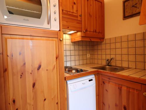 La cuisine est équipée de placards en bois, d'un évier et d'un four micro-ondes. dans l'établissement Appartement 2 Pièces + Coin Montagne, Idéal Familles, au Pied des Pistes, Les Allues - FR-1-182-2, à Méribel