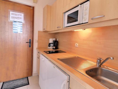 une petite cuisine avec un évier et un micro-ondes dans l'établissement Charmant studio lumineux skis aux pieds avec balcon et Wi-Fi - FR-1-182-8, à Méribel