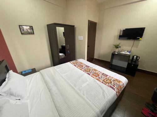 a hotel room with a bed and a flat screen tv at The Blue Burrows Homestay in Kalimpong
