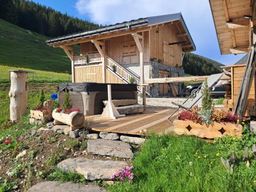 une cabane en rondins avec une terrasse et une maison dans l'établissement Chez Merlin, à Glières-Val-de-Borne