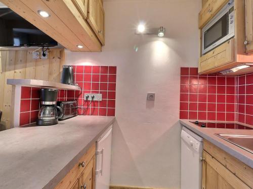 - une cuisine avec du carrelage rouge sur le mur dans l'établissement Studio Divisible Idéalement Situé, Skis aux Pieds et Proche des Commerces - FR-1-182-194, à Les Allues