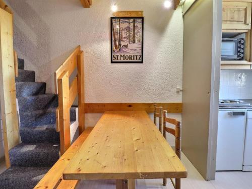 une table en bois dans une chambre avec un escalier dans l'établissement Duplex 3 Pièces pour 6 Pers. avec Wi-Fi à Méribel - FR-1-182-176, à Méribel