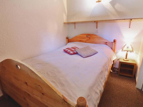 - une chambre avec un lit en bois et 2 oreillers dans l'établissement Appartement Chaleureux sur Pistes - Balcon, 4 Pers, Bien Équipé, Proche Commodités - FR-1-182-52, à Méribel