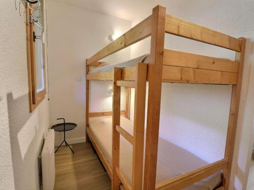 Ce lit superposé se trouve dans une petite chambre avec une table. dans l'établissement Studio cosy avec balcon, à deux pas des pistes et commerces au Châtelet - FR-1-182-86, à Méribel