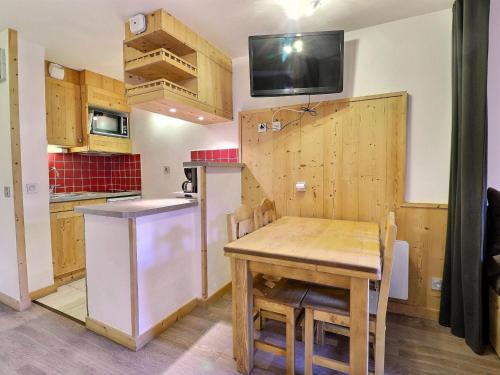 une cuisine et une salle à manger avec une table en bois dans l'établissement Studio 3* pour 4 pers. avec balcon, skis aux pieds, proche commerces et remontées mécaniques - FR-1-182-193, à Les Allues