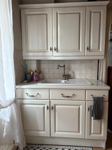 une salle de bain avec un lavabo et un meuble blanc dans l'établissement Maison de campagne de Jenny, à Peyrat-de-Bellac