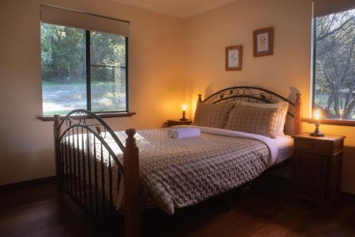 a bedroom with a bed and two windows at #4 Walpole Wilderness Resort chalet - Spa & Forest! in Walpole