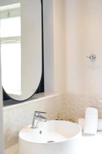 a bathroom with a white sink and a mirror at Elena Village Hotel & Suites in Kalymnos
