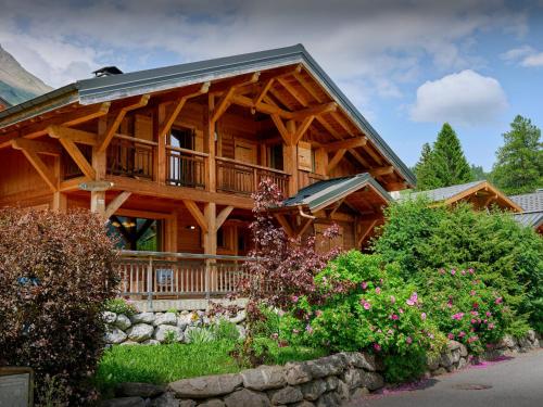 une grande maison en bois avec un porche et quelques fleurs dans l'établissement Chalet La Canopée - OVO Network, à La Giettaz