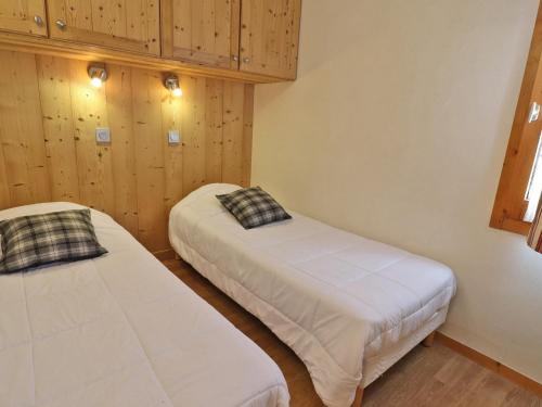 deux lits dans une chambre aux murs en bois dans l'établissement Appartement au pied des pistes, proche commerces, 4 pers, Wi-Fi gratuit, animaux admis - FR-1-182-201, à Les Allues