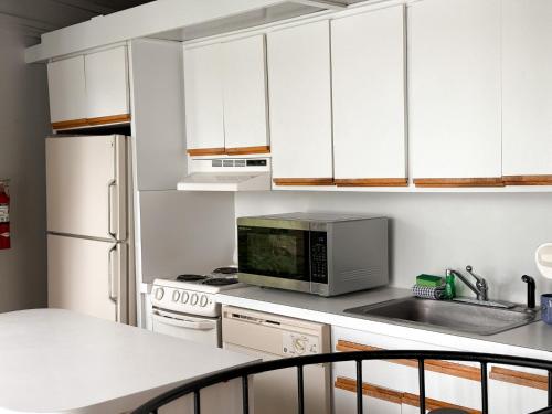 a kitchen with white cabinets and a sink and a microwave at Treetop-forest Flatsunit22 -four Seasons in Four Seasons