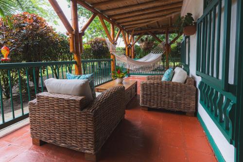 two wicker chairs and a hammock on a porch at Hacienda Bambusa in El Caimo