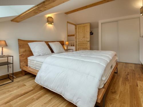 une chambre avec un grand lit blanc et du parquet dans l'établissement Bel appartement neuf 8 pers près du village avec Wifi et garage - FR-1-642-100, à Samoëns