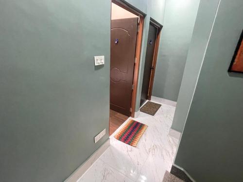 a bathroom with a door and a rug on the floor at The Blue Burrows Homestay in Kalimpong