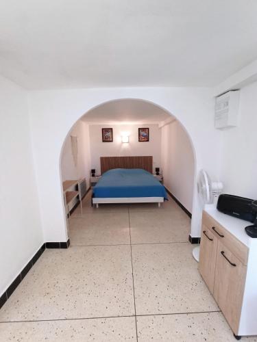 une chambre avec un lit bleu dans une pièce blanche dans l'établissement T2 en rez de jardin d'une villa à saint aygulf à 800 m d'une calanque-mer à pied, à Fréjus