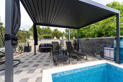 a patio with a swimming pool and a black umbrella at MY DALMATIA - Apartment Nikita with private pool in Zaboric
