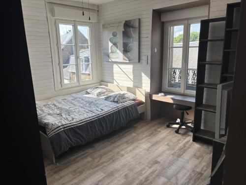 een slaapkamer met een bed en een bureau en twee ramen bij Maison de ville avec jardin clos in Carrouges