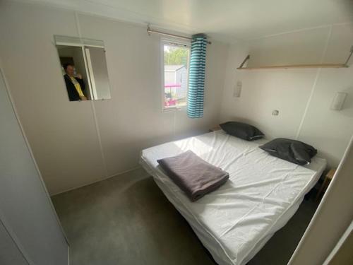 Cette petite chambre blanche comprend un lit avec deux oreillers. dans l'établissement Mobil home camping Marisol toreilles, à Torreilles