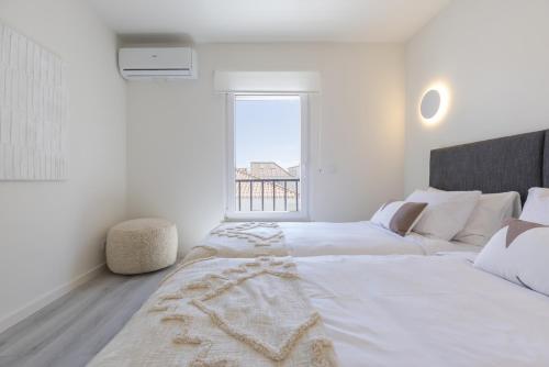 a white bedroom with two beds and a window at Peniche Hideout in Peniche
