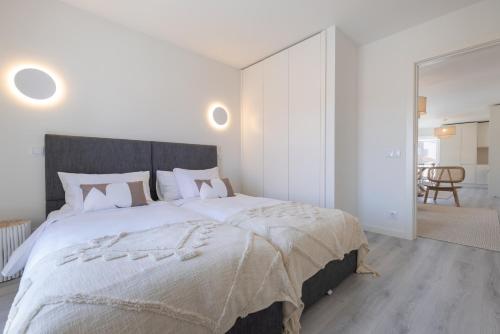a white bedroom with a large bed with white sheets at Peniche Hideout in Peniche