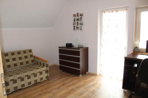 a living room with a chair and a dresser at Dom Wakacyjny na wyłączność - Ranczo Nowosiółki - Kresowe Klimaty in Nowosiółki