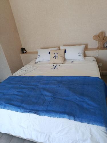 a bed with blue and white sheets and pillows at Tigmi Anis Essaouira Diabat in Essaouira