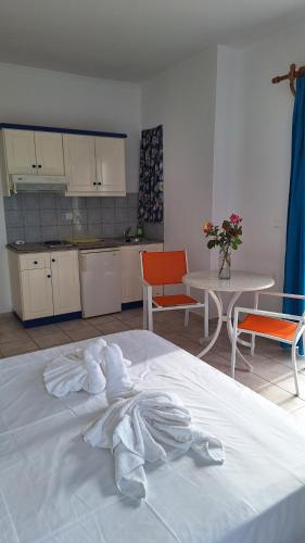 a white bed in a room with a table and chairs at Kalliopi Studios - Apartments in Kato Daratso