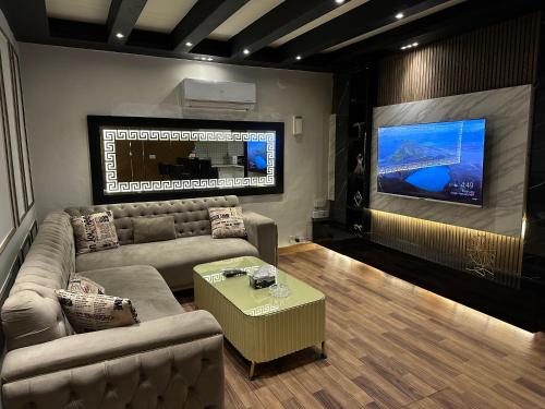 een woonkamer met een bank en een flatscreen-tv bij 1 Bedroom Luxury Apartment in F-10 in Islamabad