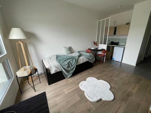 Cette chambre comprend un lit, une table et une cuisine. dans l'établissement Bright and peaceful studio with extendable bed, à Palaiseau