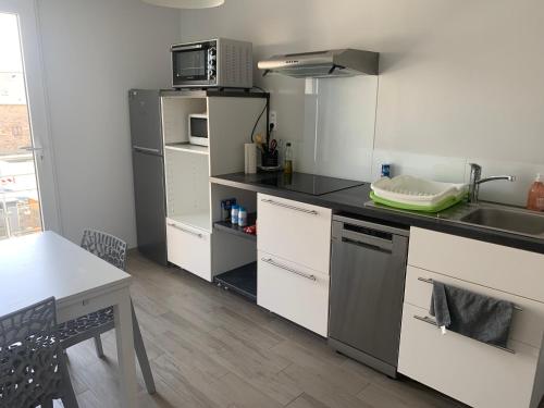 une cuisine avec un réfrigérateur, un évier et une table dans l'établissement Appartement 1er étage, à Lannion